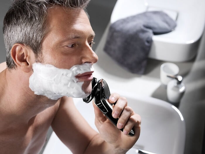 man uses Philips Norelco SensoTouch 3D/1250x shaver in bathroom