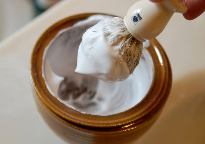 shaving lather in wooden bowl taken out with brush