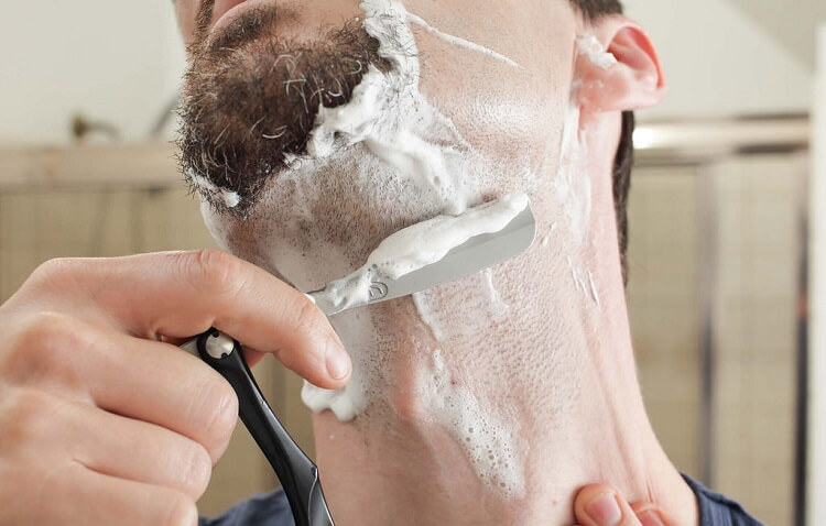 man shaving with a straight razor